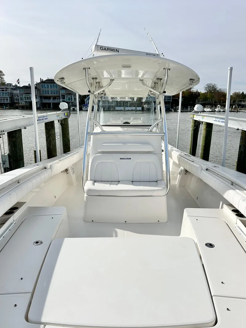 Slide: The Image of 2015 Regulator 34 boat docked, featuring spacious deck and seating, with waterfront view. - 13