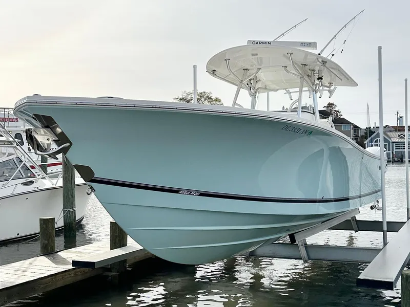 Slide: The Image of 2015 Regulator 34 boat docked, showcasing sleek design and light blue hull. - 5