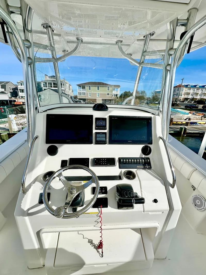 Slide: The Image of 2015 Regulator 34 boat cockpit with dual screens and steering wheel, docked in a marina. - 8
