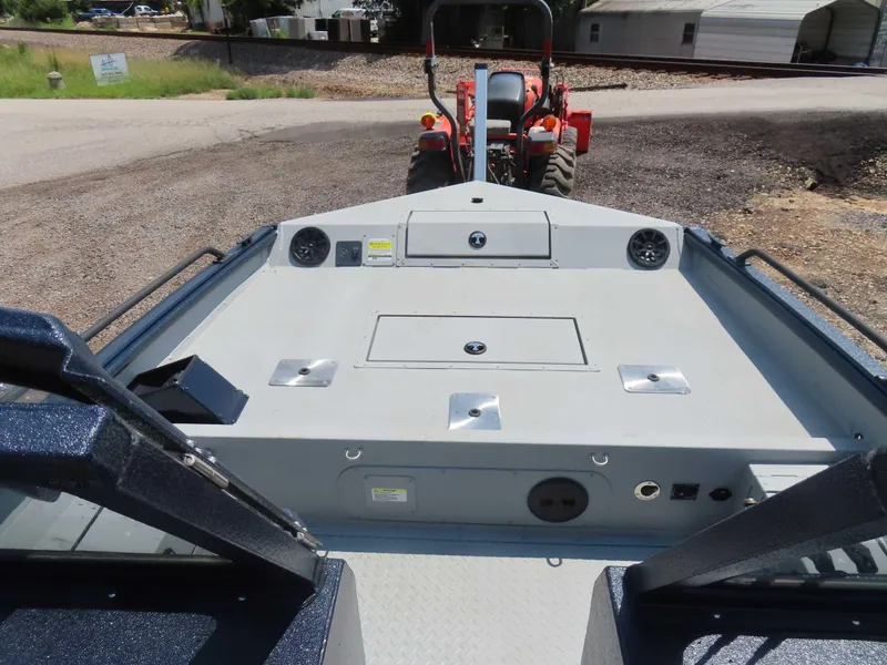 Slide: The Image of 2024 SeaArk Pro Guide 2672 boat interior with storage compartments and a tractor in the background. - 4