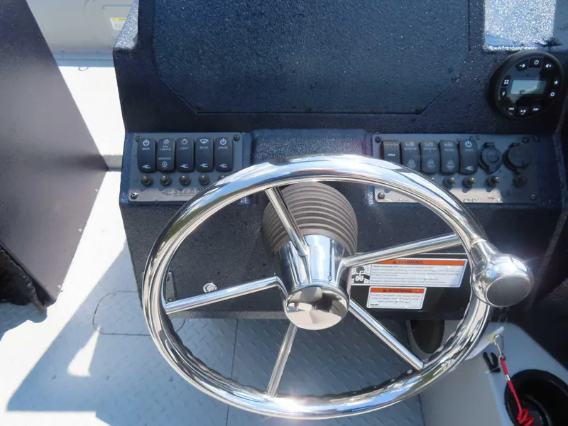 Slide: The Image of 2024 SeaArk Pro Guide 2672 boat helm with chrome steering wheel and control panel. - 9
