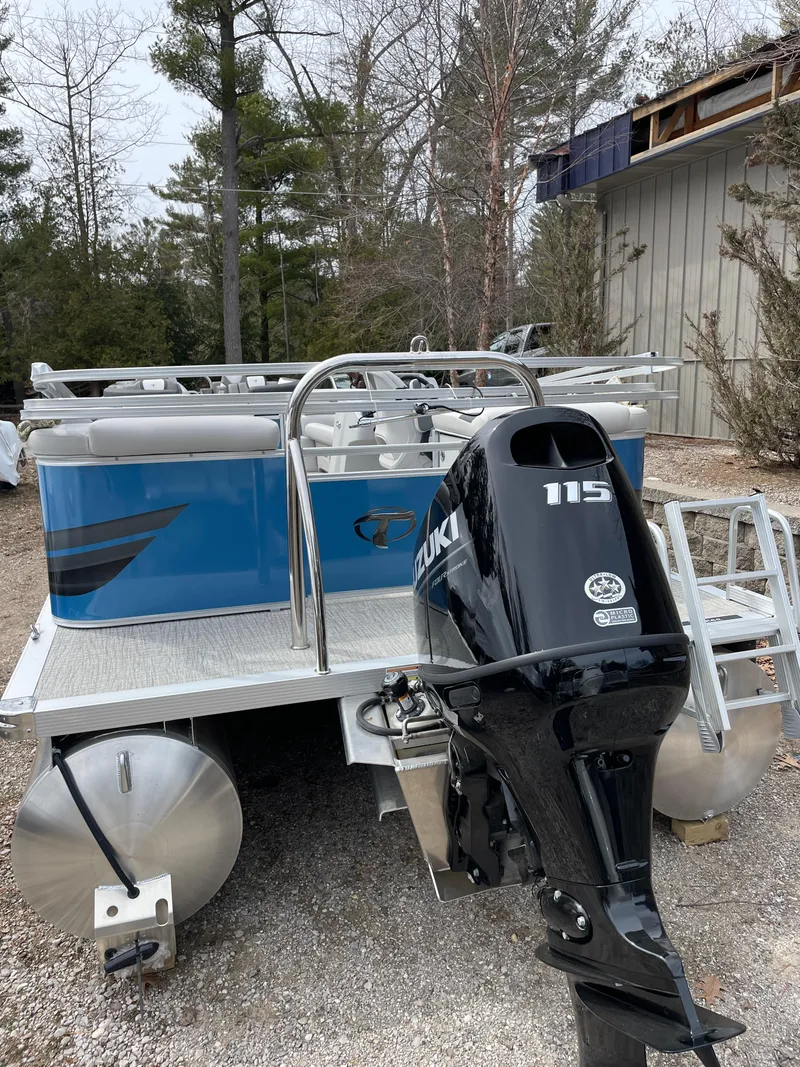 Slide: The Image of 2025 Tahoe 21 Sport 85 pontoon boat with Suzuki 115 outboard motor, parked outdoors. - 9