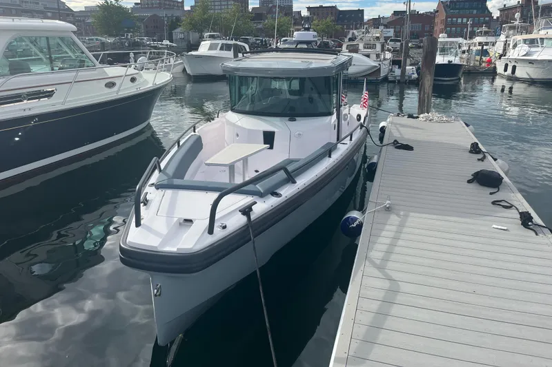 Slide: The Image of 2022 Axopar 28 Cabin with Brabus Package docked in a marina. - 2