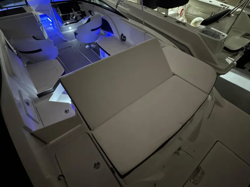 Slide: The Image of 2019 Sea Ray SPX 230 boat interior with blue ambient lighting and white seating. - 15