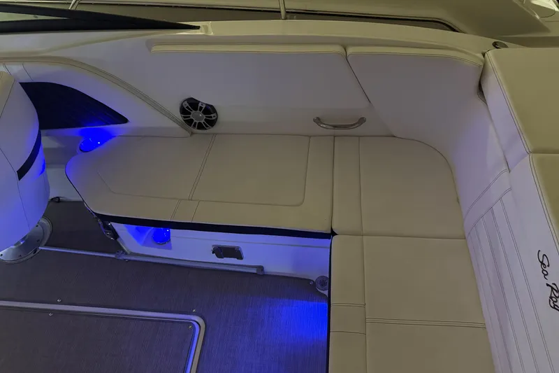 Slide: The Image of 2019 Sea Ray SPX 230 boat interior with white seating and blue LED lighting. - 16