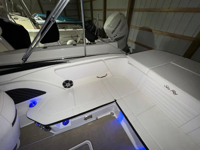 Slide: The Image of 2019 Sea Ray SPX 230 boat interior with white seating and blue LED lighting. - 7