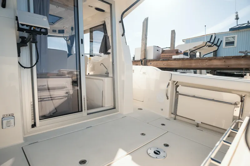 Slide: The Image of 2024 Bayliner Trophy T25 Pilothouse boat interior with sliding door and deck view. - 14