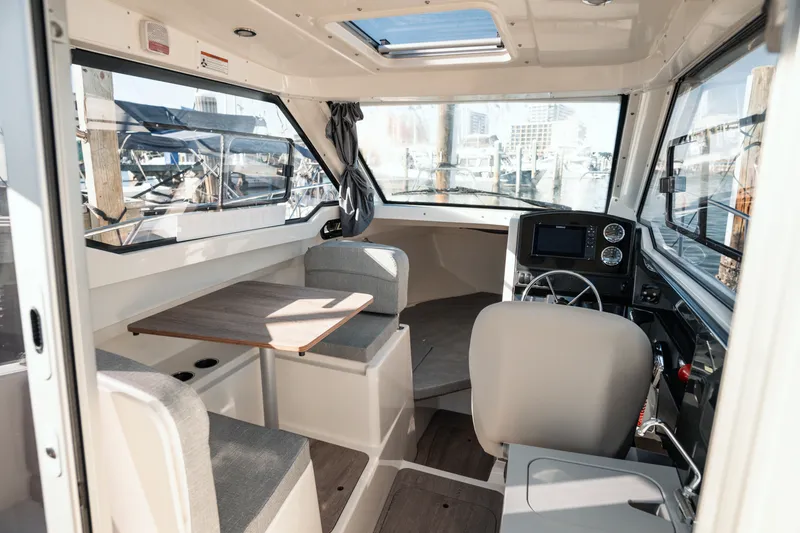 Slide: The Image of 2024 Bayliner Trophy T25 Pilothouse interior with seating, table, and helm. - 15