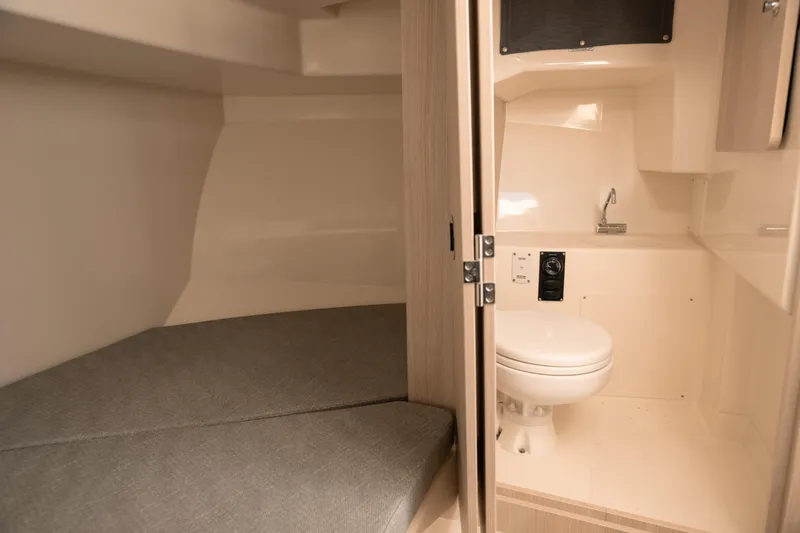 Slide: The Image of 2024 Bayliner Trophy T25 Pilothouse interior with bed and compact bathroom. - 9