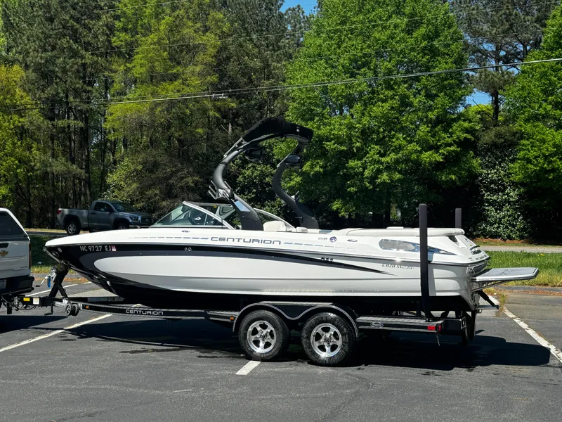 Slide: The Image of 2012 Centurion Enzo SV230 boat on trailer in parking lot, surrounded by trees. - 21