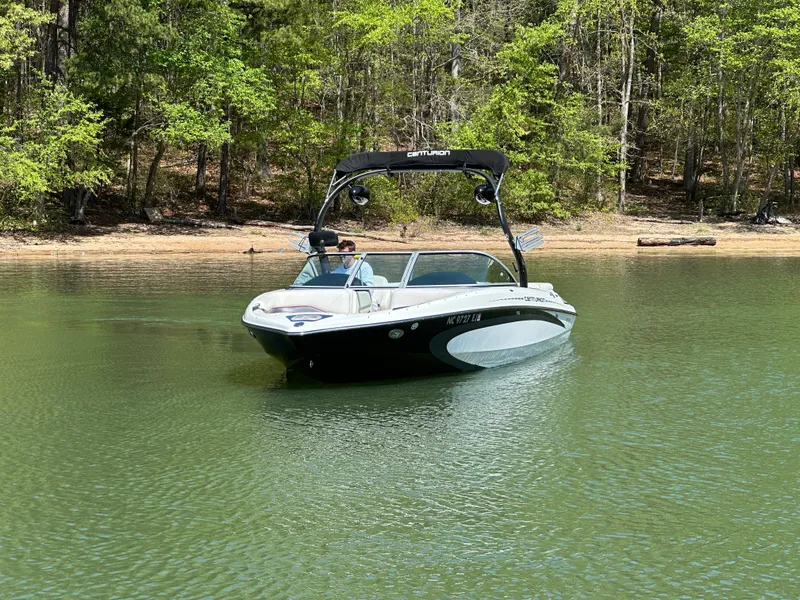 Slide: The Image of 2012 Centurion Enzo SV230 boat cruising on a serene lake near a wooded shoreline. - 4