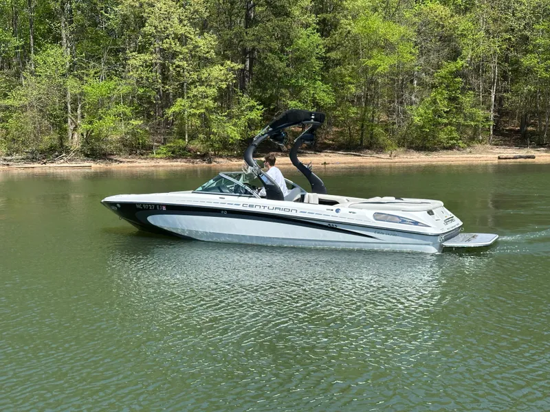 Slide: The Image of 2012 Centurion Enzo SV230 boat cruising on a calm lake with forested shoreline. - 5