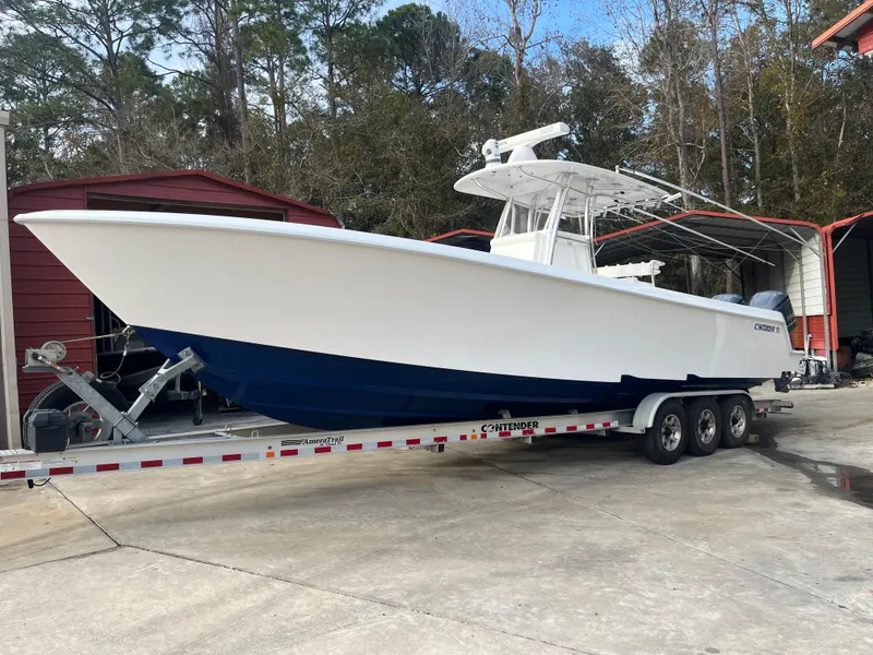 Slide: The Image of 2016 Contender 35 ST boat on trailer, white hull, blue bottom, parked outdoors. - 23