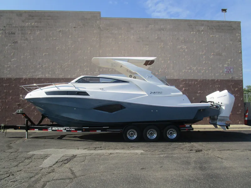 The Image of 2025 NX Boats 290 on trailer, sleek design, dual outboard engines, parked outdoors. - 1