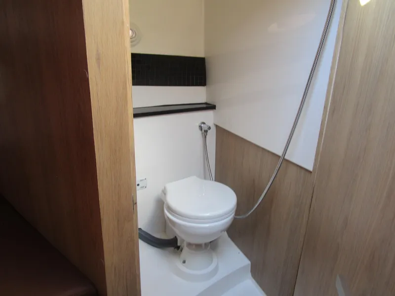 Slide: The Image of 2025 NX Boats 290 bathroom with modern toilet and shower, featuring wood paneling. - 15