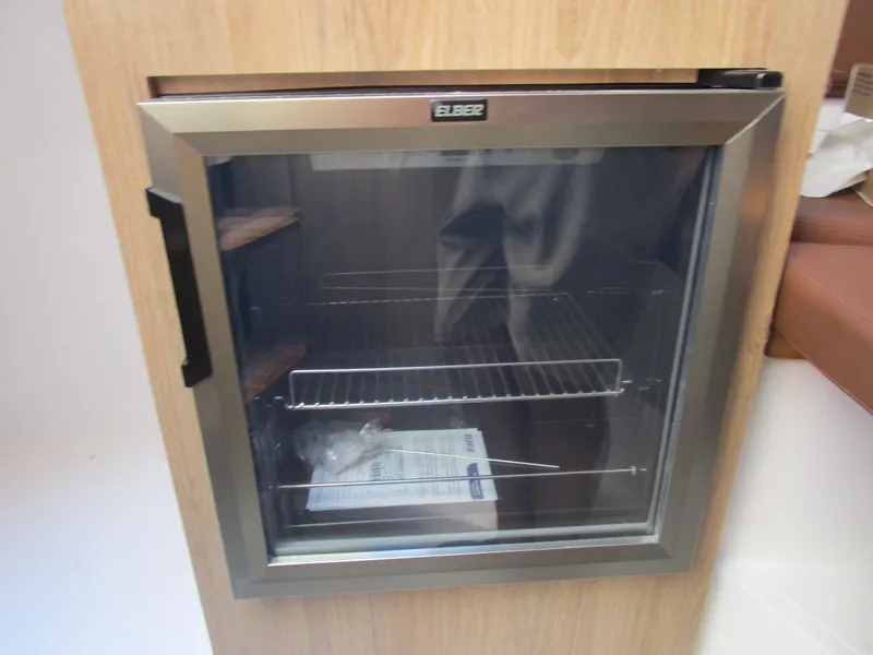 Slide: The Image of Small glass-front refrigerator inside NX Boats 290, 2025 model. - 17