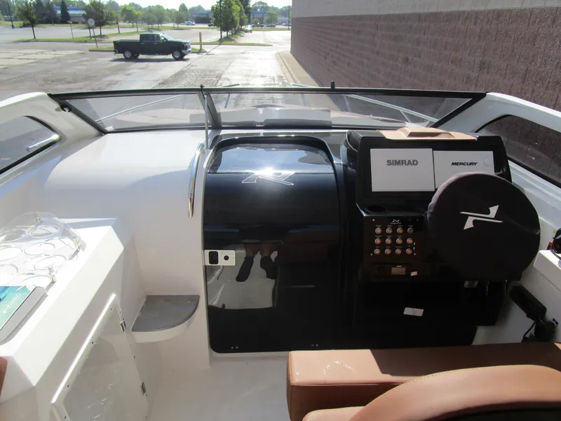 Slide: The Image of 2025 NX Boats 290 dashboard with Simrad and Mercury controls, brown seating, and cup holders. - 18