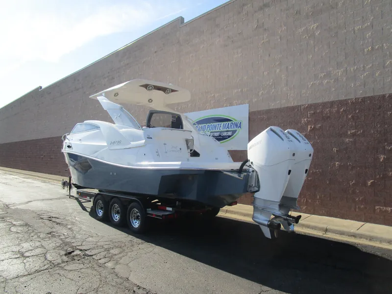 Slide: The Image of 2025 NX Boats 290 on trailer, parked near a marina wall. - 3