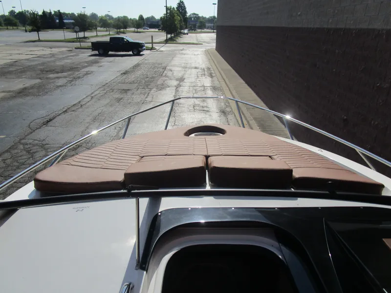 Slide: The Image of 2025 NX Boats 290 with sunpad, parked in an empty lot. - 8