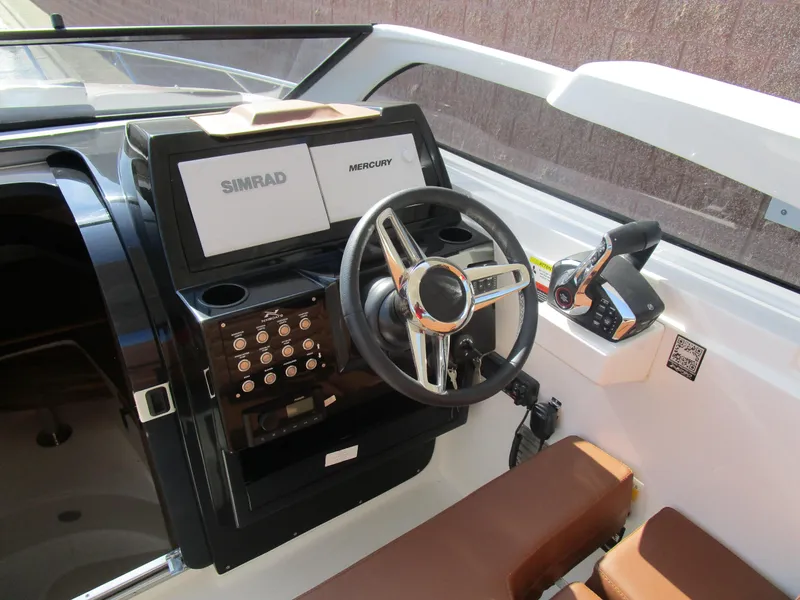 Slide: The Image of 2025 NX Boats 290 helm with Simrad and Mercury controls, modern steering wheel, and brown seating. - 9