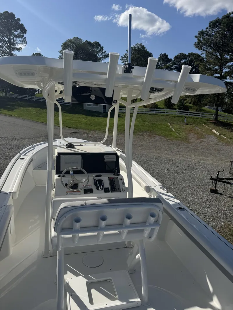 Slide: The Image of 2025 Parker 23 SE CC boat with center console and rod holders, parked outdoors. - 5