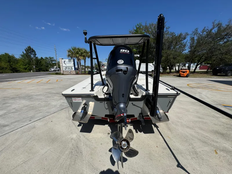 Slide: The Image of 2024 Hewes Redfisher 16 boat with outboard motor, parked outdoors on a sunny day. - 13