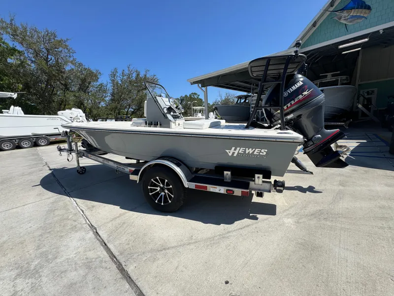 Slide: The Image of 2024 Hewes Redfisher 16 boat on trailer, parked outdoors near a building. - 17