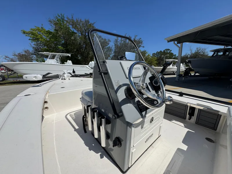 Slide: The Image of 2024 Hewes Redfisher 16 boat console with steering wheel, docked under clear blue sky. - 21