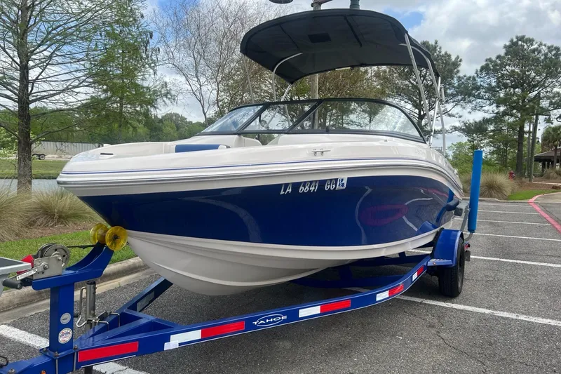 Slide: The Image of 2016 Tahoe TAH450TS boat on trailer in parking lot, surrounded by trees. - 3