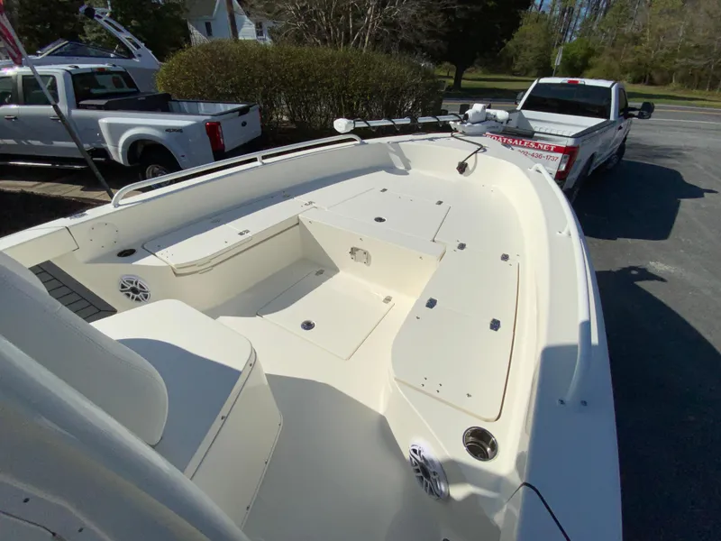 Slide: The Image of 2025 Pathfinder 2600 TRS boat with spacious deck, parked near pickup trucks. - 22
