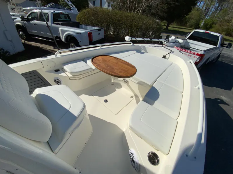 Slide: The Image of 2025 Pathfinder 2600 TRS boat with seating and wooden table, parked near trucks. - 34