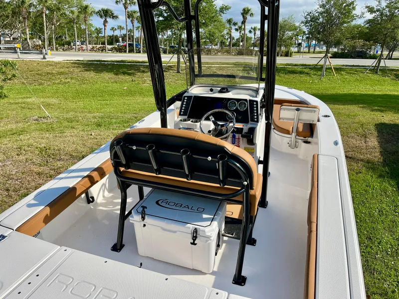 Slide: The Image of 2025 Robalo 226 Cayman boat interior with seating and console, parked on grass. - 10