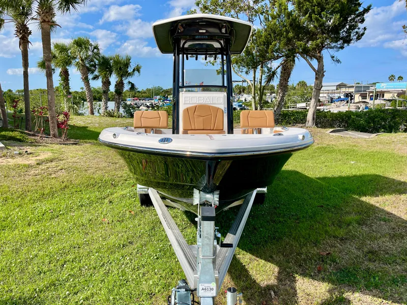 Slide: The Image of 2025 Robalo 226 Cayman boat on trailer, parked on grass with trees in background. - 3