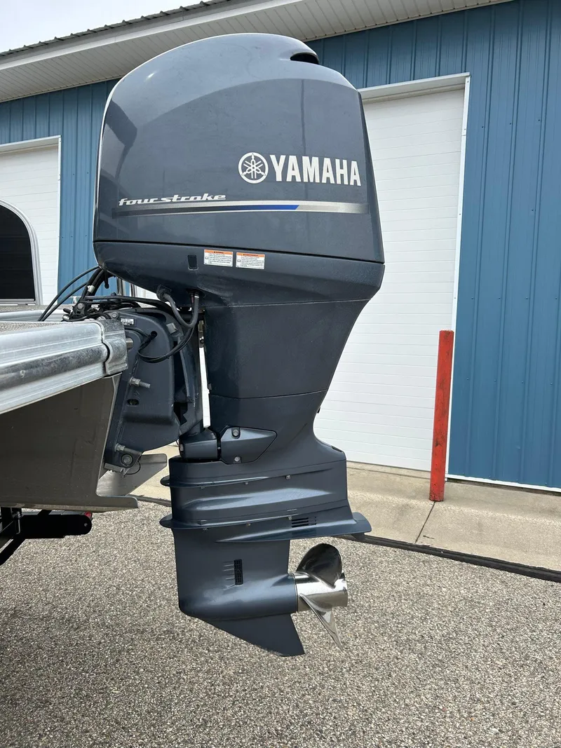 Slide: The Image of 2014 Bennington 2550 RCL with Yamaha four-stroke outboard motor, parked near blue building. - 11