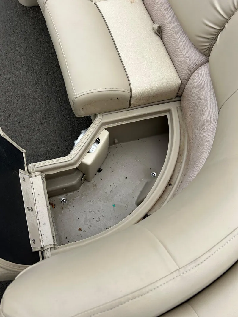 Slide: The Image of 2014 Bennington 2550 RCL boat interior with open storage compartment and beige seating. - 21