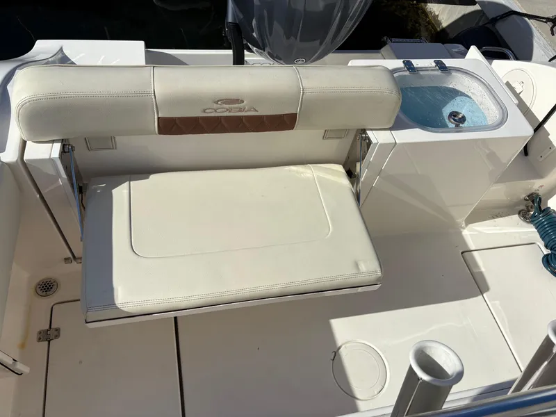 Slide: The Image of 2023 Cobia 237 CC boat interior with cushioned seating and built-in sink. - 14