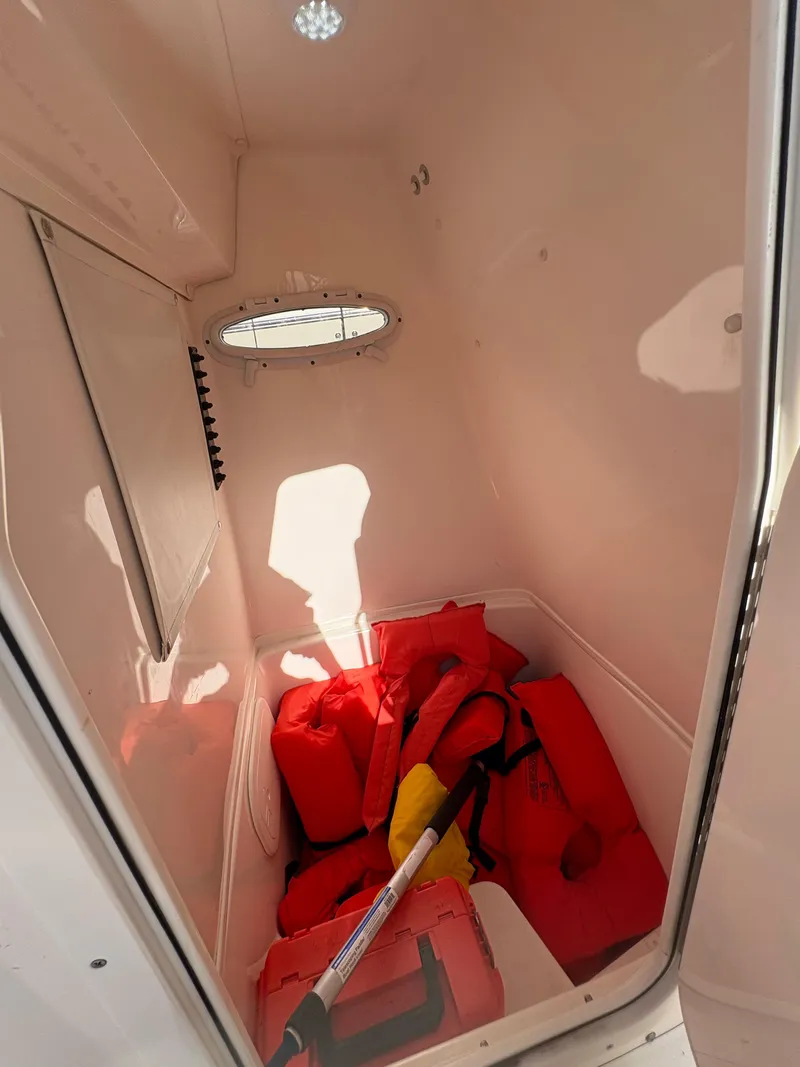 Slide: The Image of 2023 Cobia 237 CC storage area with life jackets and equipment. - 18