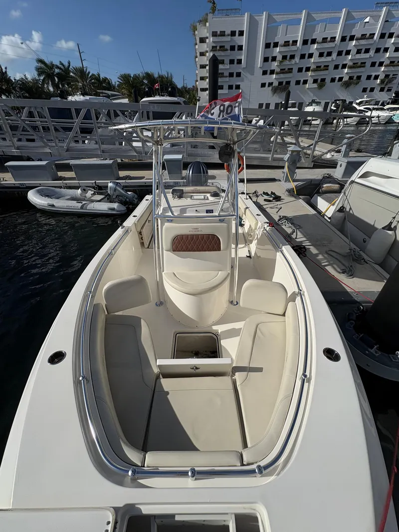Slide: The Image of 2023 Cobia 237 CC boat docked at marina, featuring spacious seating and modern design. - 3