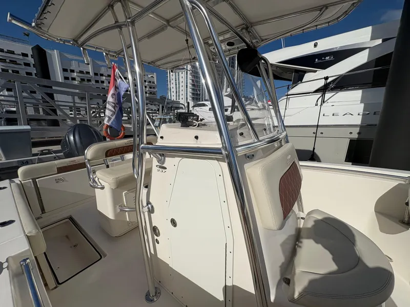 Slide: The Image of 2023 Cobia 237 CC boat with T-top and seating, docked at marina. - 4