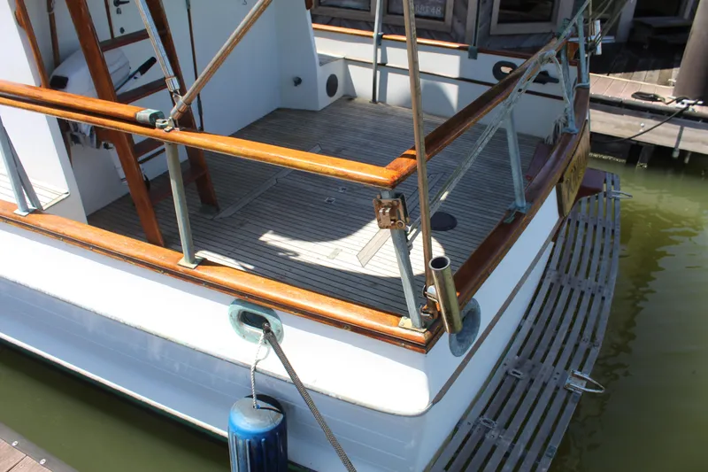 Slide: The Image of 1978 Grand Banks 32 boat stern with wooden deck and railing, docked in calm water. - 14