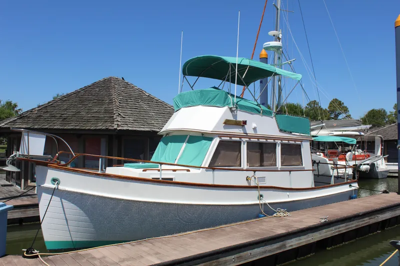 Slide: The Image of 1978 Grand Banks 32 boat docked, featuring teal canopy and classic wooden design. - 2