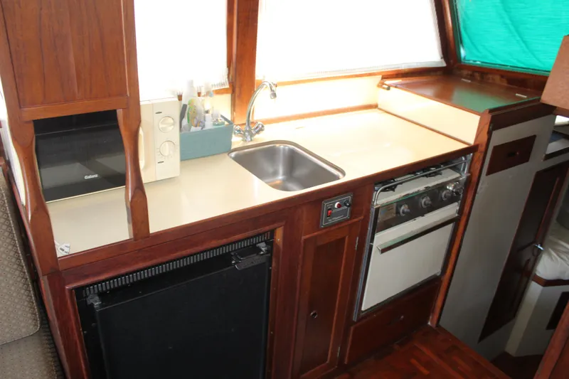 Slide: The Image of 1978 Grand Banks 32 yacht kitchen with sink, stove, and wooden cabinetry. - 27
