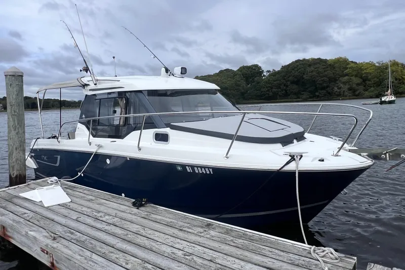 Slide: The Image of 2019 Jeanneau NC 795 boat docked on a calm river under cloudy skies. - 0