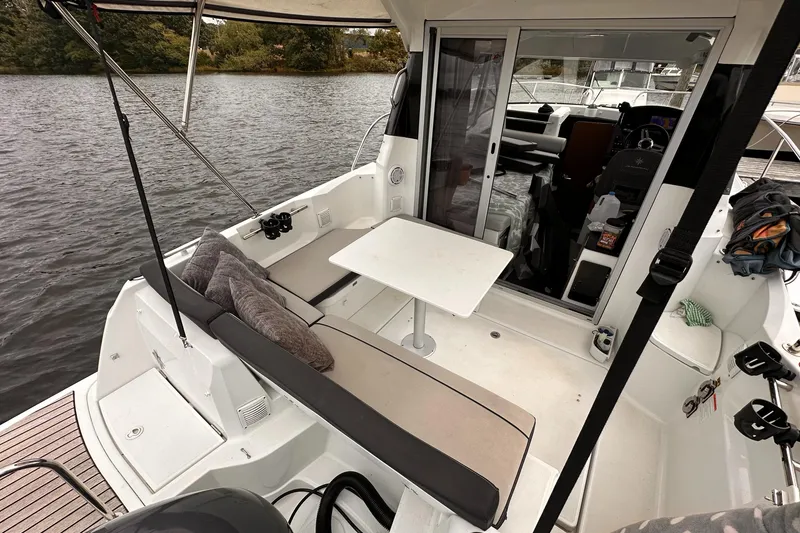 Slide: The Image of 2019 Jeanneau NC 795 boat with outdoor seating and table on a calm river. - 11