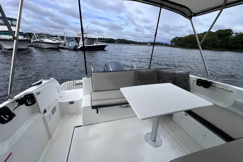 Slide: The Image of 2019 Jeanneau NC 795 boat interior with seating and table, docked on a calm lake. - 12