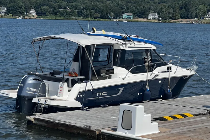 Slide: The Image of 2019 Jeanneau NC 795 boat docked with Yamaha engine, featuring fishing rods and paddleboards. - 4