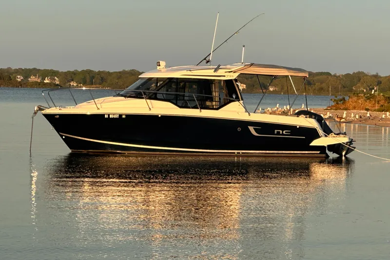 Slide: The Image of 2019 Jeanneau NC 795 boat anchored on calm water at sunset. - 5