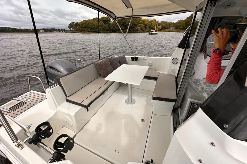 Slide: The Image of 2019 Jeanneau NC 795 boat interior with seating and table on a calm lake. - 9