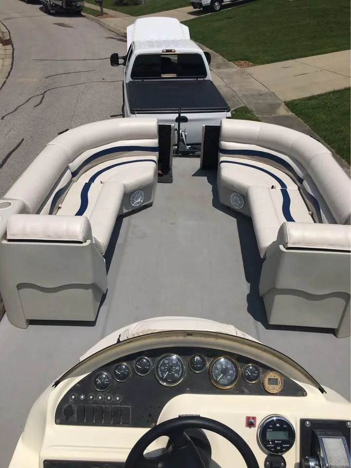 Slide: The Image of 2000 Crest Ultra ET pontoon boat interior with plush seating, parked on a residential street. - 10