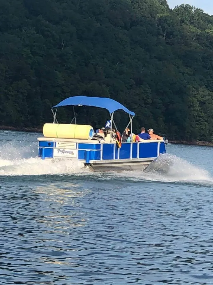 Slide: The Image of Blue Crest Ultra ET pontoon boat cruising on a lake, surrounded by lush greenery. - 15